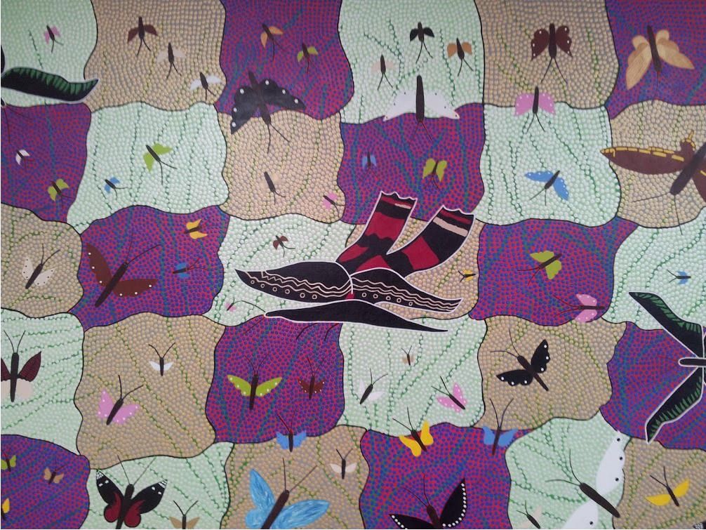 A dot painting of butterflies over patches of purple, green and sand-coloured country